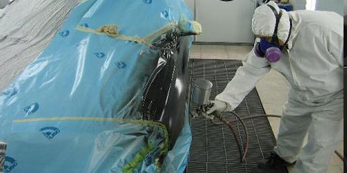 Technician spraying primer on a car in the workshop