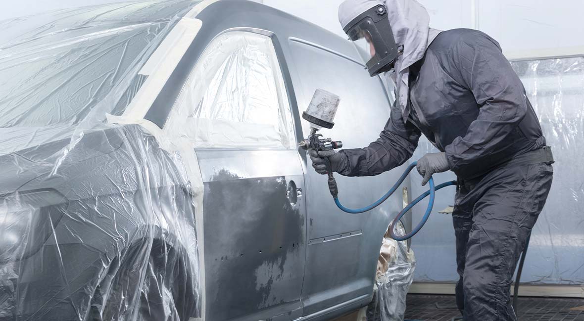 Technician spray painting a car in the paint booth